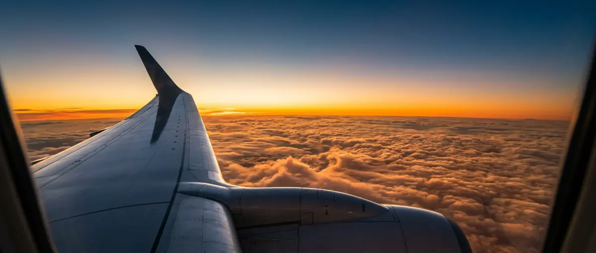 Aircraft wing above a sea of sunset clouds from a window seat